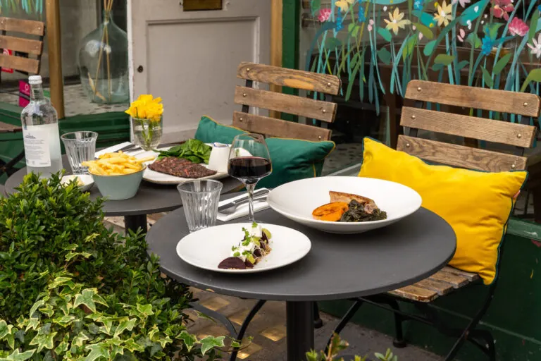 An outdoor table set for two on the pavement outside Manuka Kitchen on Fulham Road