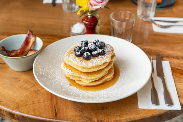 A stack of blueberry pancakes with maple syrup