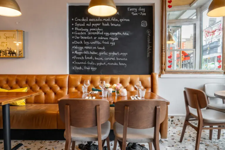 Dining tables at Manuka Kitchen with the day's dishes chalked on a black menu board